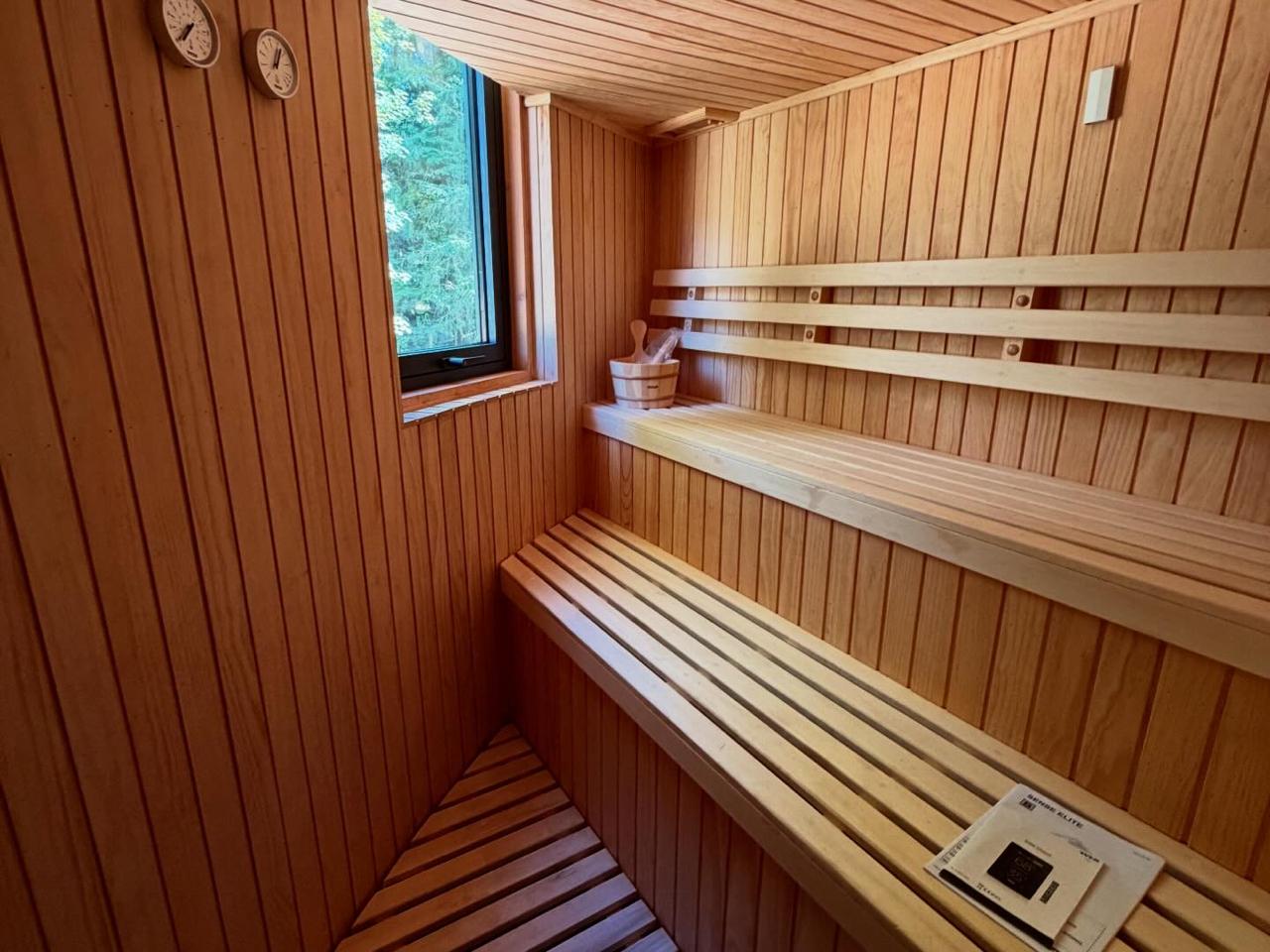 Fachada de casa de dos pisos con revestimiento oscuro y grandes ventanales termopanel